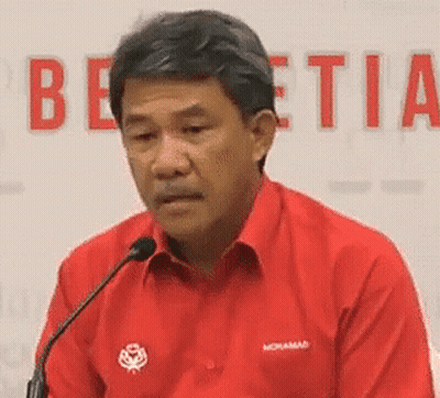 A Man In A Red Shirt Is Sitting At A Microphone . GIF