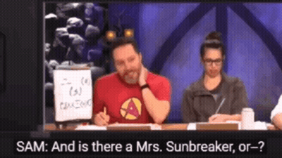 A Man In A Red Shirt Is Sitting At A Table Talking To A Woman In A Grey Jacket GIF