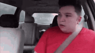 A Man In A Red Shirt Is Sitting In A Car . GIF