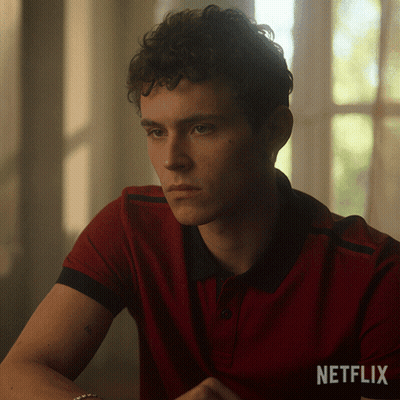 A Man In A Red Shirt Is Sitting In Front Of A Window With A Netflix Logo Behind Him GIF