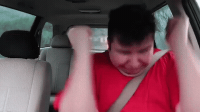 A Man In A Red Shirt Is Sitting In The Back Seat Of A Car GIF