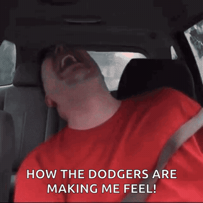 A Man In A Red Shirt Is Sitting In The Back Seat Of A Car And Laughing GIF