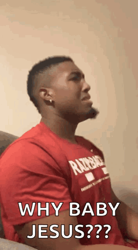 A Man In A Red Shirt Is Sitting On A Couch . GIF