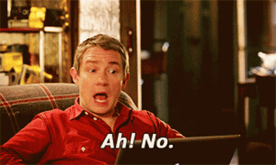 A Man In A Red Shirt Is Sitting On A Couch Looking At A Laptop And Saying Ah No GIF