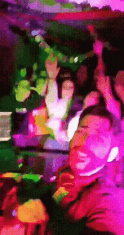 A Man In A Red Shirt Is Smiling In Front Of A Group Of People GIF