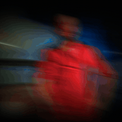 A Man In A Red Shirt Is Standing In A Dark Room With Smoke Behind Him GIF