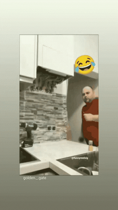 A Man In A Red Shirt Is Standing In A Kitchen With A Yellow Smiley Face Behind Him GIF