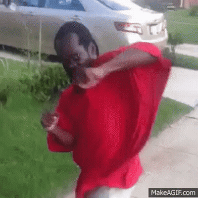 A Man In A Red Shirt Is Standing In Front Of A Car GIF