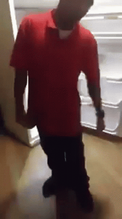 a man in a red shirt is standing in front of a fridge