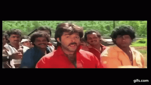 A Man In A Red Shirt Is Standing In Front Of A Group Of Men . GIF