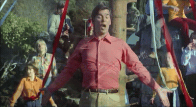 A Man In A Red Shirt Is Standing In Front Of A Group Of People GIF