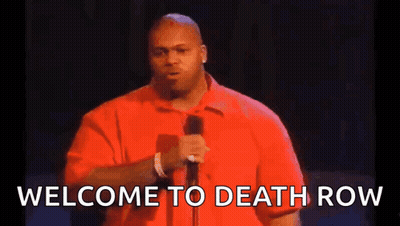 A Man In A Red Shirt Is Standing In Front Of A Microphone And Saying Welcome To Death Row . GIF
