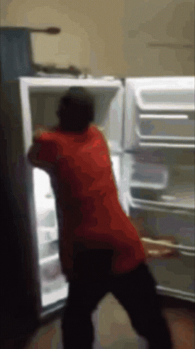A Man In A Red Shirt Is Standing In Front Of A Refrigerator GIF