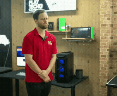 A Man In A Red Shirt Is Standing In Front Of A Sign That Says Play Hard Tech GIF