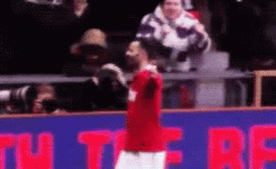 A Man In A Red Shirt Is Standing In Front Of A Sign That Says ' U ' On It GIF