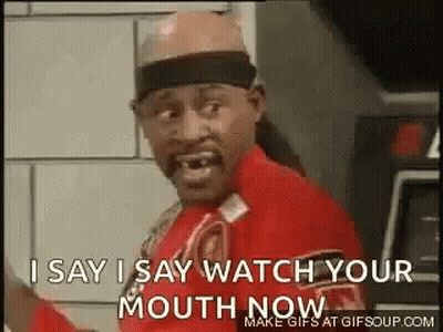 A Man In A Red Shirt Is Standing In Front Of A Wall And Says `` I Say I Say Watch Your Mouth Now '' . GIF
