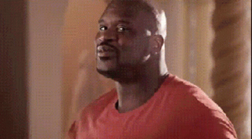 A Man In A Red Shirt Is Standing In Front Of A Wall GIF