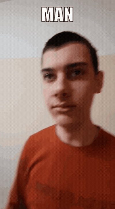 A Man In A Red Shirt Is Standing In Front Of A Wall With The Word Man Above His Head GIF