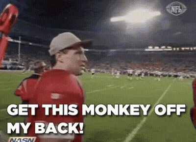 A Man In A Red Shirt Is Standing On A Football Field And Says `` Get This Monkey Off My Back '' . GIF