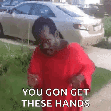 A Man In A Red Shirt Is Standing On A Sidewalk And Says `` You Gon Get These Hands '' GIF