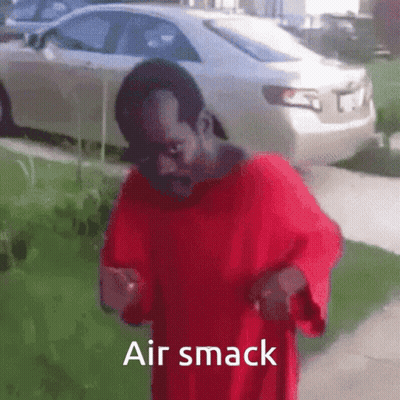 A Man In A Red Shirt Is Standing On A Sidewalk With The Words Air Smack Above Him . GIF