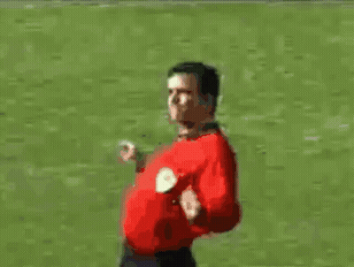 A Man In A Red Shirt Is Standing On A Soccer Field With His Arms Outstretched GIF