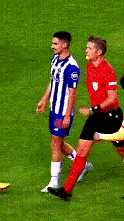 A Man In A Red Shirt Is Standing On A Soccer Field With Players GIF
