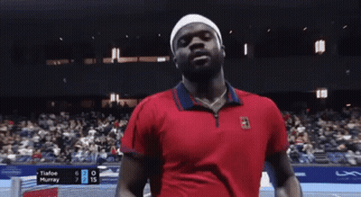 A Man In A Red Shirt Is Standing On A Tennis Court . GIF
