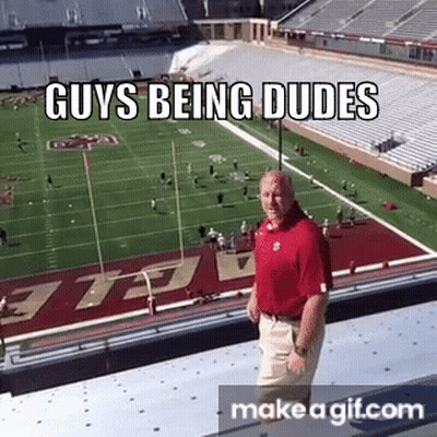 A Man In A Red Shirt Is Standing On The Edge Of A Stadium . GIF