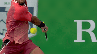 A Man In A Red Shirt Is Swinging A Tennis Racket GIF