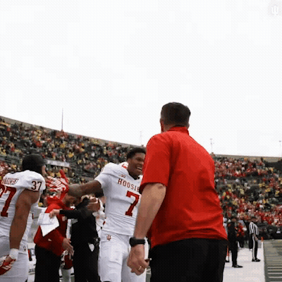 A Man In A Red Shirt Is Talking To A Football Player Wearing A Hoosier Jersey GIF