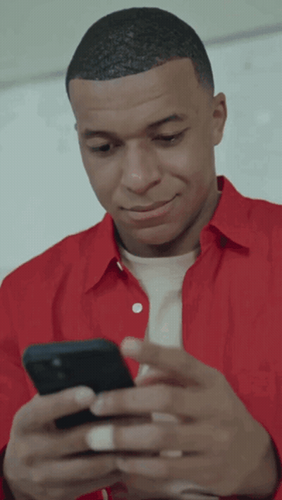 A Man In A Red Shirt Looks At His Phone GIF