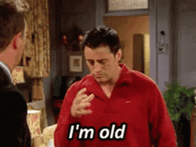 A Man In A Red Shirt Says I 'M Old While Talking To Another Man GIF