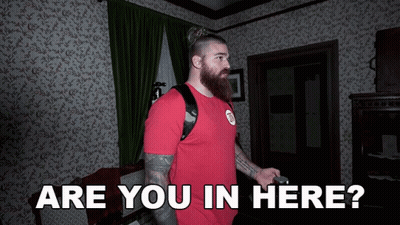 A Man In A Red Shirt Stands In A Room With The Words Are You In Here GIF