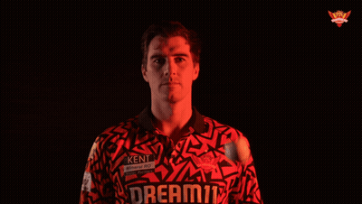 A Man In A Red Shirt Stands In Front Of A Black Background With A Crown On It GIF