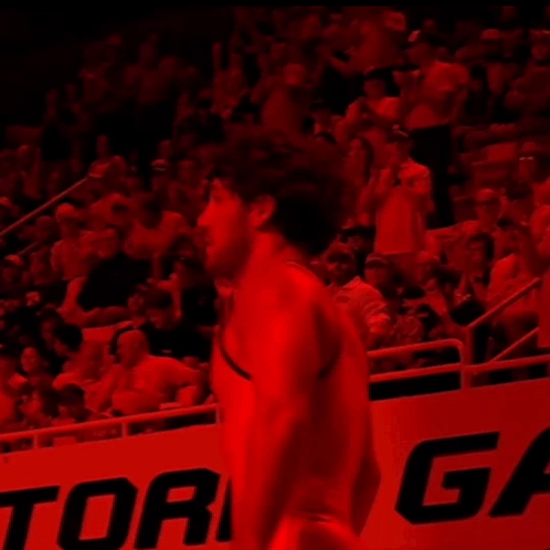 A Man In A Red Shirt Stands In Front Of A Sign That Says Ric GIF