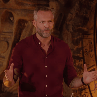 A Man In A Red Shirt Stands In Front Of A Wall With The Word Survivor On It GIF
