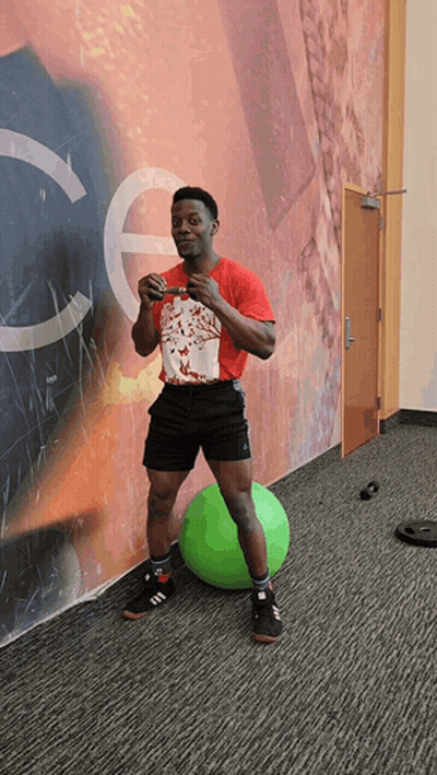 A Man In A Red Shirt Stands On A Green Ball GIF