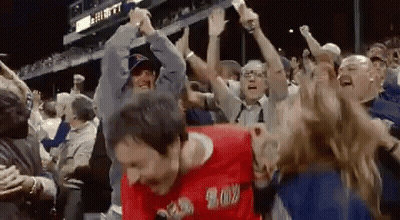 A Man In A Red Shirt That Says ' Boston ' On It Is Dancing In A Crowd Of People GIF