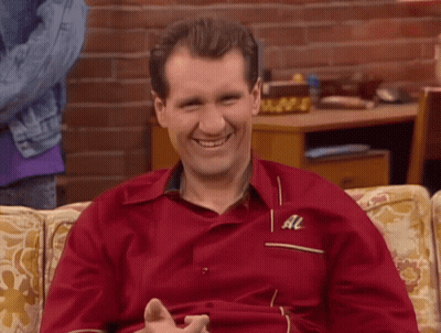 A Man In A Red Shirt With The Letter Al On The Sleeve Smiles GIF