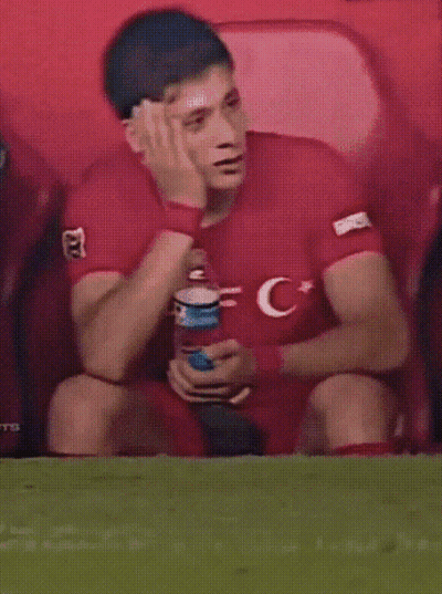 A Man In A Red Shirt With The Letter C On It Sits On The Field GIF