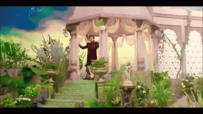 A Man In A Red Shirt With The Letter M On His Chest Is Standing In A Garden GIF
