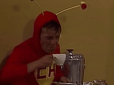 A Man In A Red Shirt With The Letter P On It Drinking A Cup Of Coffee GIF