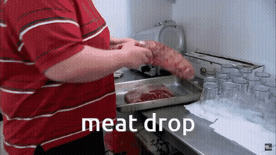A Man In A Red Striped Shirt Is Holding A Large Piece Of Meat In Front Of A Tray That Says " Meat Drop " GIF