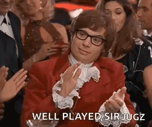 A Man In A Red Suit And Glasses Is Clapping In A Crowd Of People . GIF