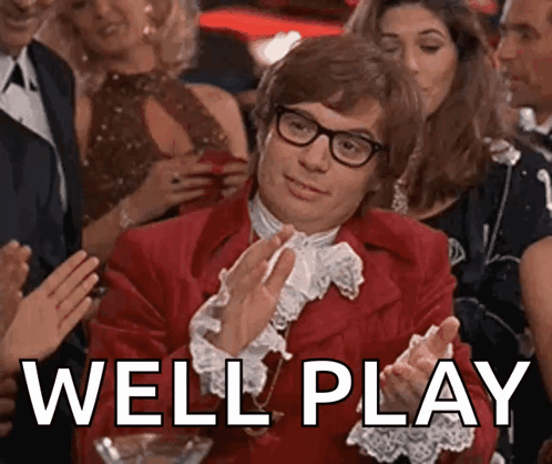 A Man In A Red Suit And Glasses Is Clapping In Front Of A Crowd . GIF