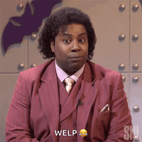 A Man In A Red Suit And Tie Says Welp In Front Of A Bat GIF