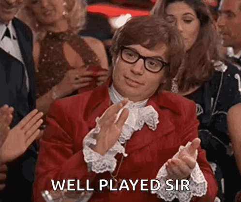 A Man In A Red Suit Is Clapping His Hands In A Crowd Of People . GIF