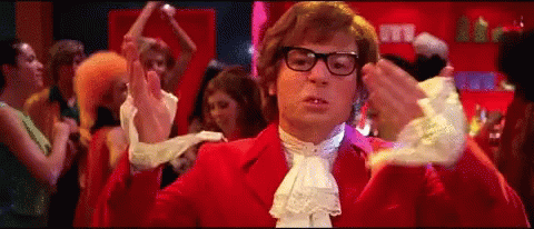 A Man In A Red Suit Is Dancing In Front Of A Crowd Of People . GIF