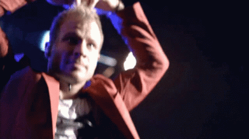A Man In A Red Suit Is Dancing On Stage GIF